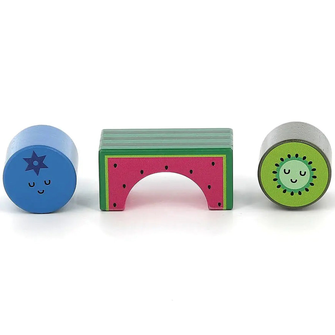 Drie Vilac houten blokken in de vorm van een blauwe bosbes, een watermeloenboog en een kiwi, met vrolijke gezichtjes.