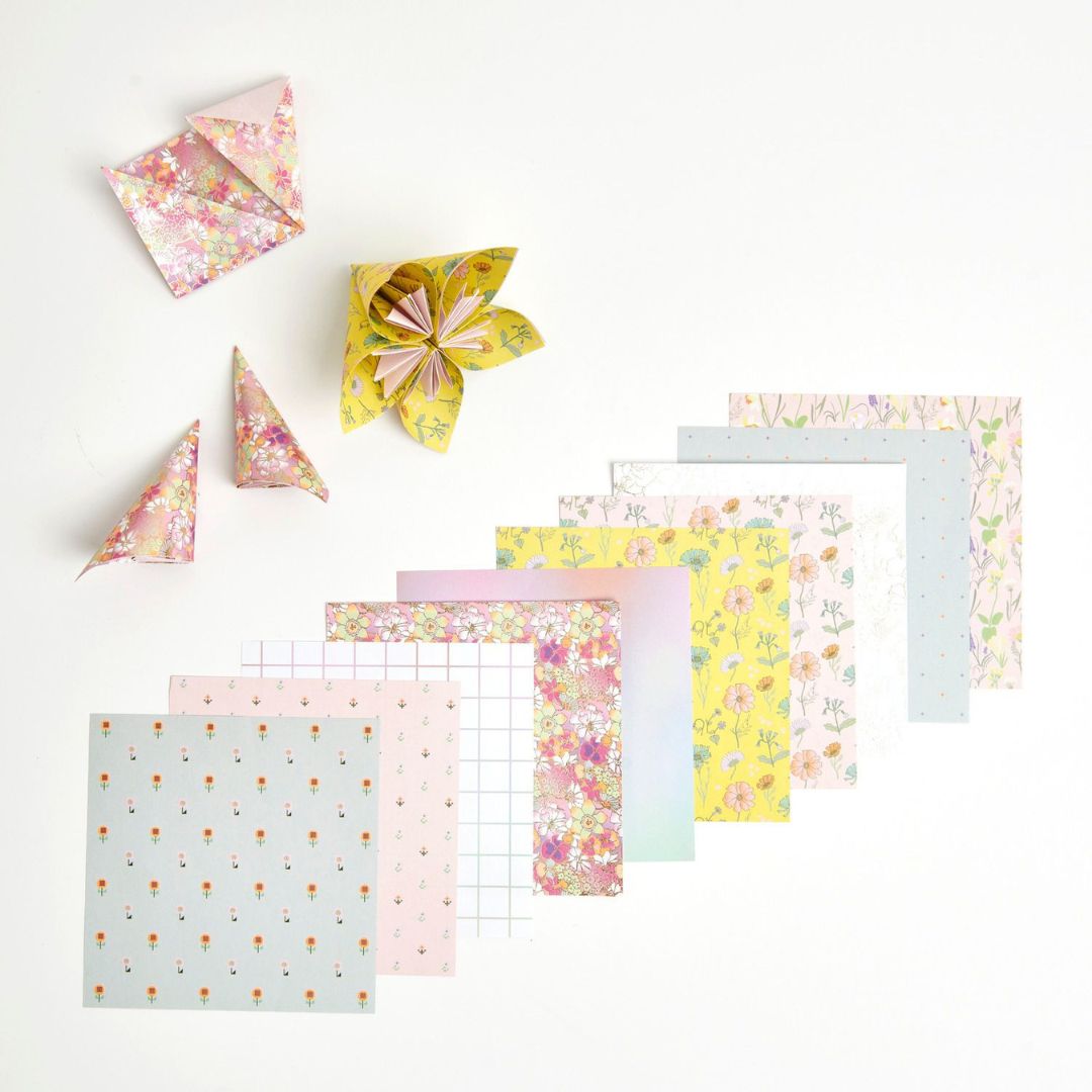 Verschillende vellen Rico Design origamipapier met diverse patronen, waarvan enkele gevouwen tot bloemen en kegels.