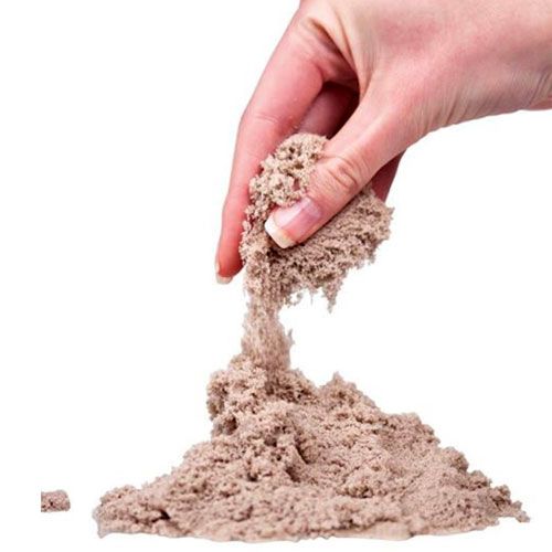 Een hand laat beige Kinetic Sand vallen op een hoopje zand.