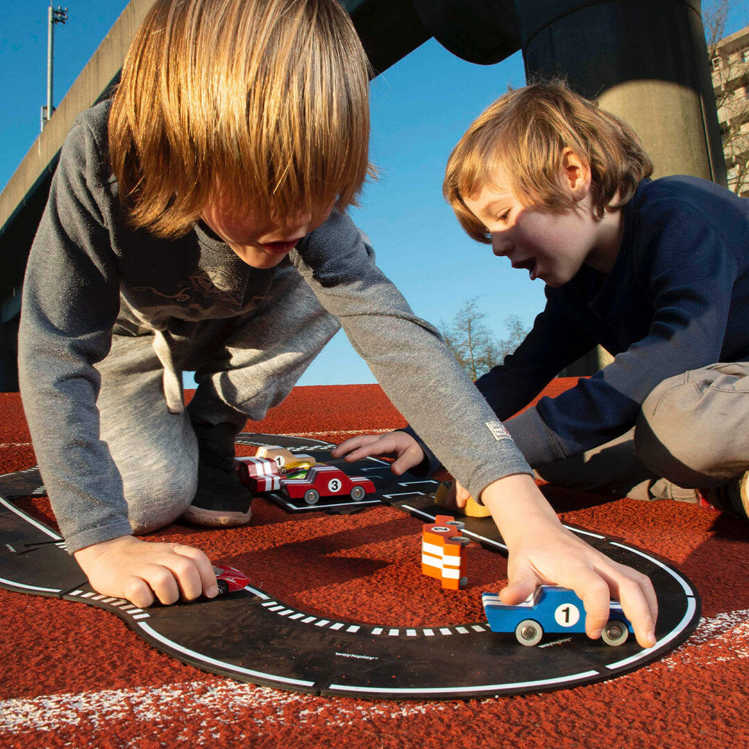 Twee kinderen spelen gehurkt met de waytoplay rubberen racebaan en speelgoedraceauto's.