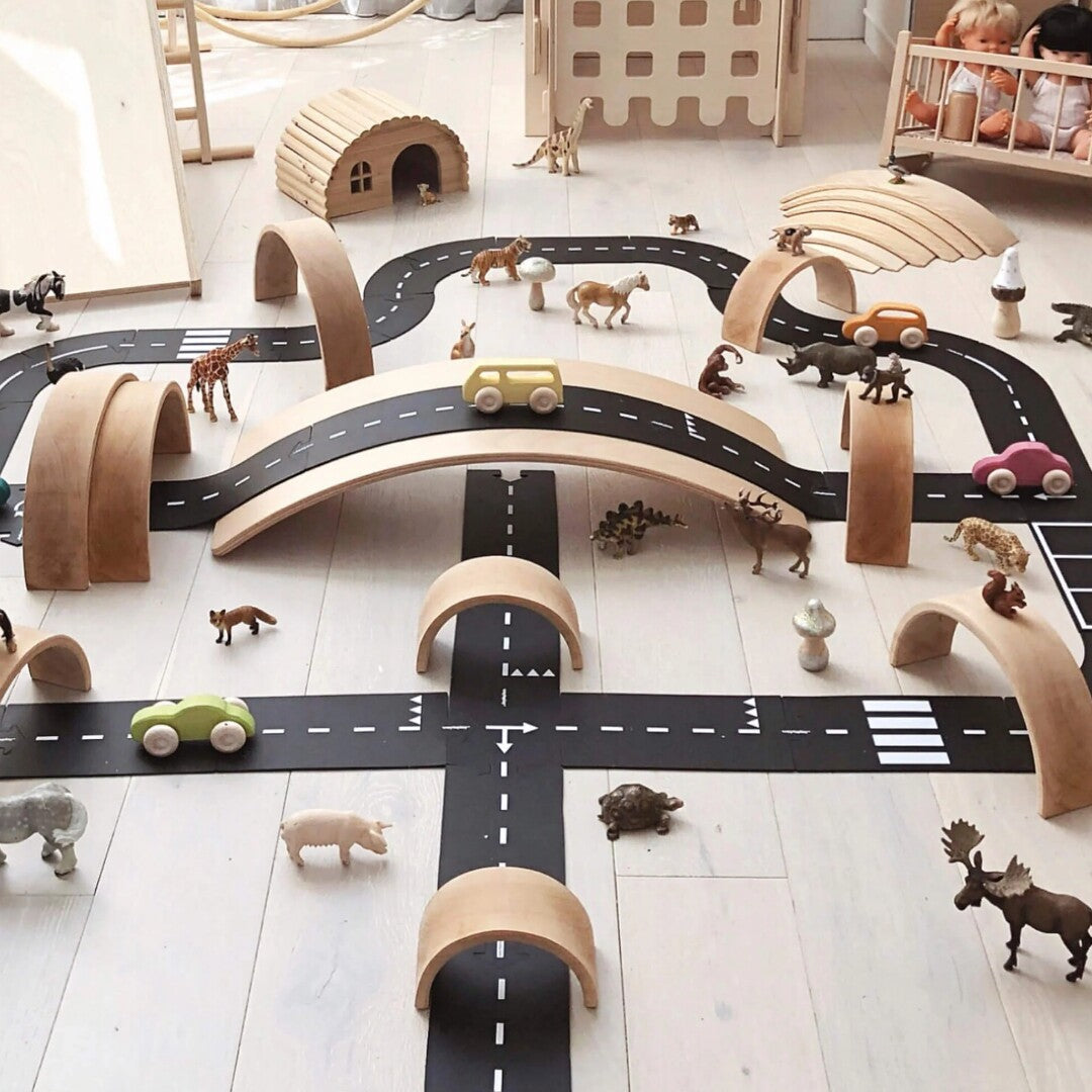 Een uitgebreide speelopstelling met een waytoplay rubberen weg, houten bruggen en diverse speelgoeddieren en auto's.