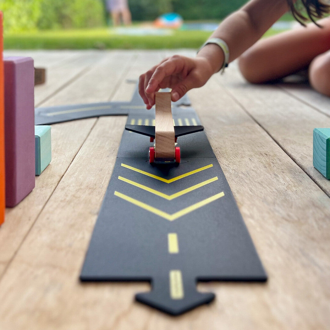 Een kind speelt met een houten vliegtuigje op een waytoplay runway speelbaan.