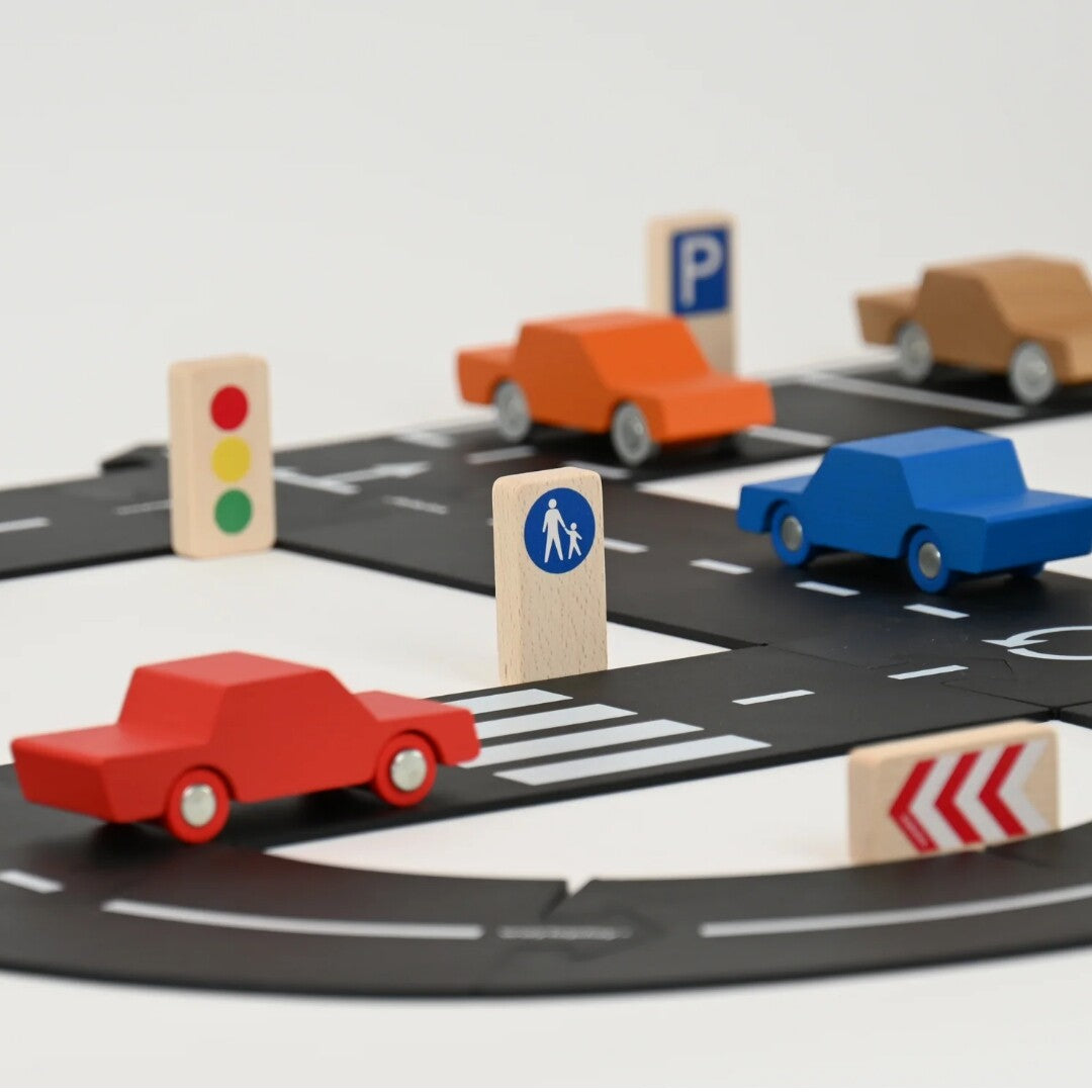Een speelscène met waytoplay houten verkeersborden, auto's en een zwarte wegmat.