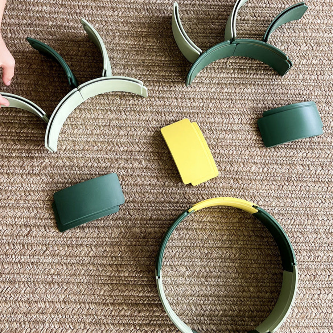 Een bovenaanzicht van diverse waytoplay boogstukken en samengestelde structuren in groen, lichtgroen en geel op een vloerkleed.