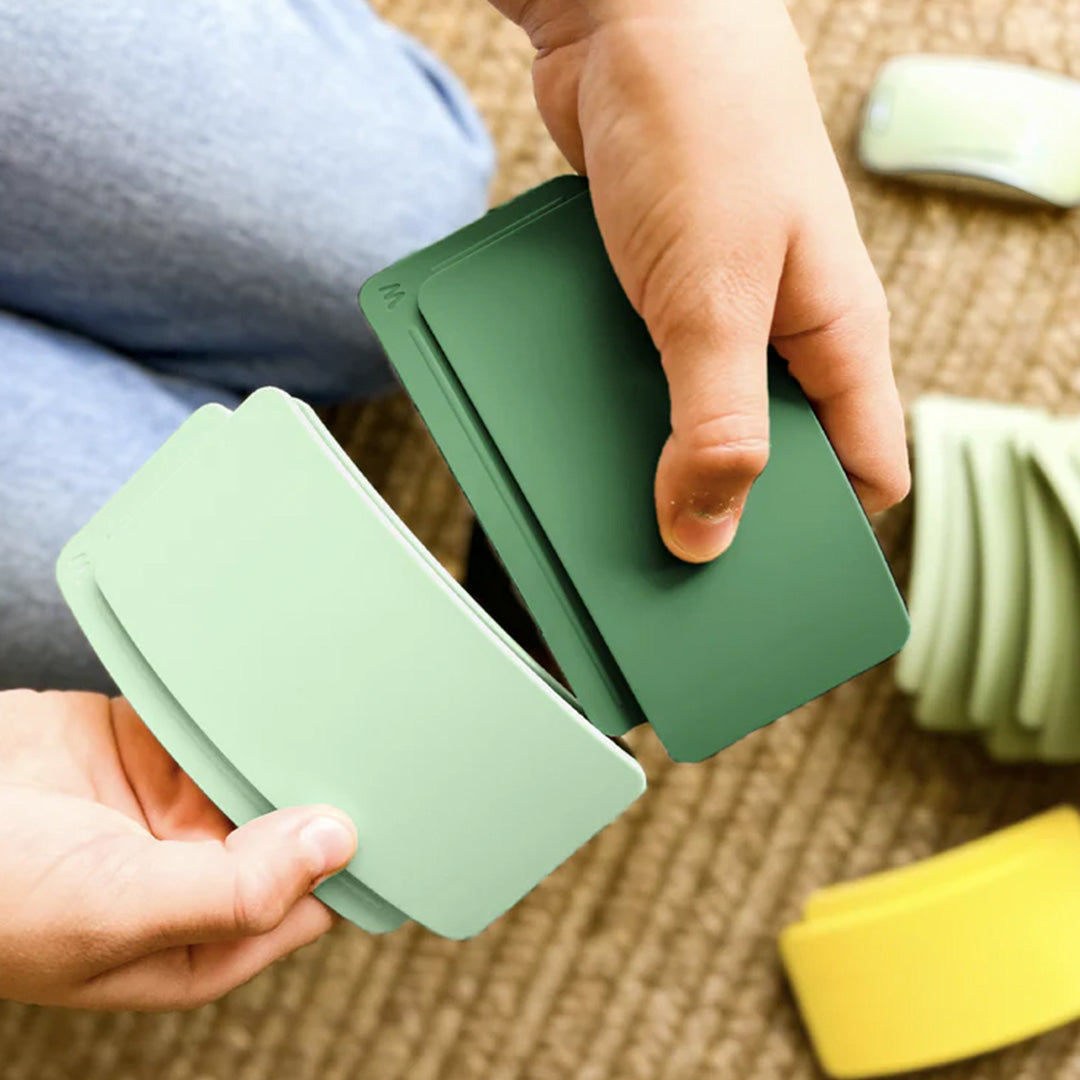 Twee handen die twee groene waytoplay boogstukken van het bouwspeelgoed in elkaar schuiven.