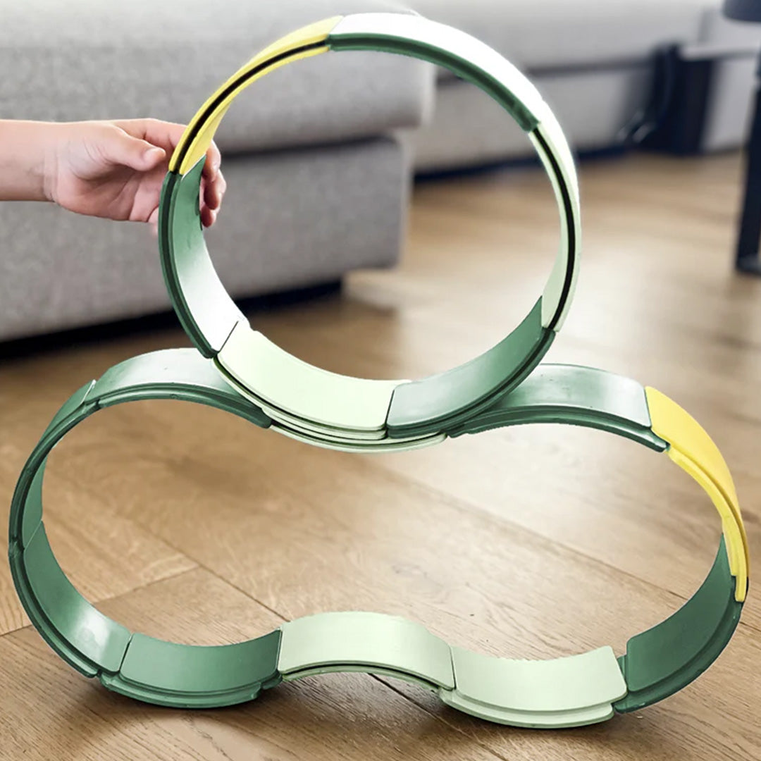Een kind bouwt met de groene en gele waytoplay boogstukken een cirkel en een figuur-acht op een houten vloer.