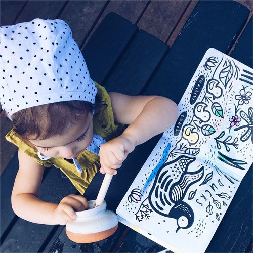 Een baby met een stippenmuts speelt op een donkere ondergrond met het badboekje dat openligt bij een pagina met eenden.