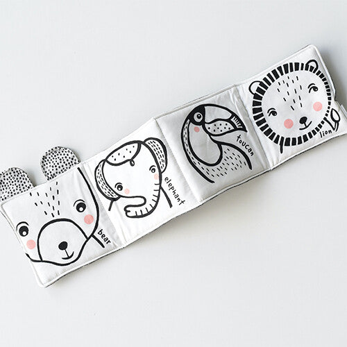 Uitgevouwen stoffen babyspeelboekje met zwart-witte illustraties van een beer, olifant, toekan en leeuw.