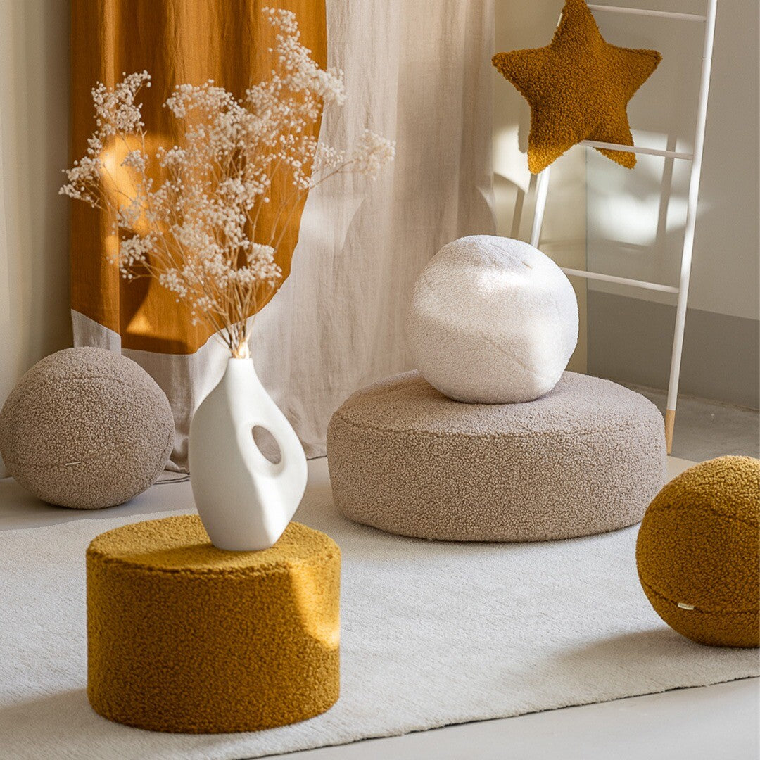 Een collectie wigiwama poefs en kussens in beige en geel in een interieur.