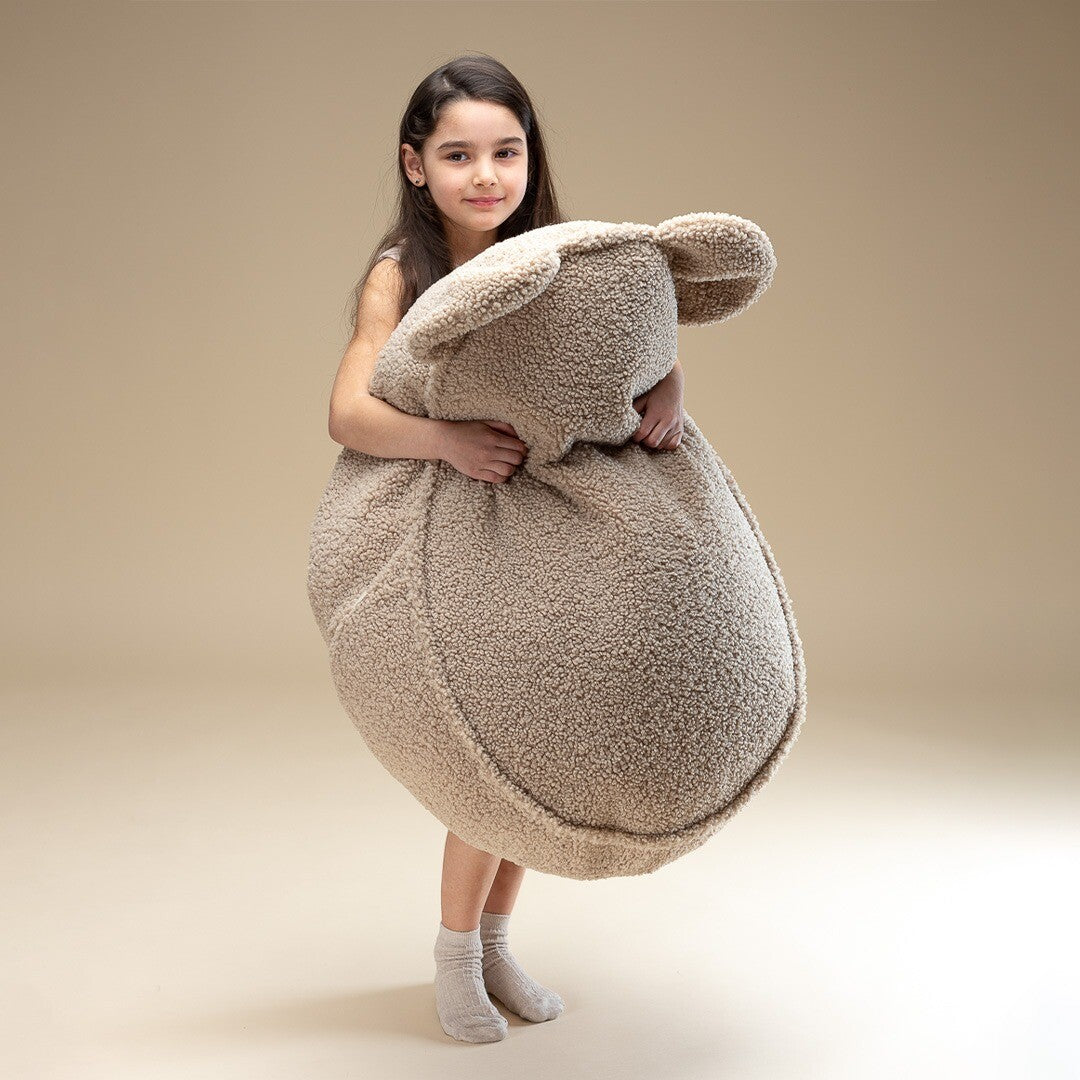 Meisje houdt de Wigiwama beige zitzak met berenoren vast om de grootte te tonen.