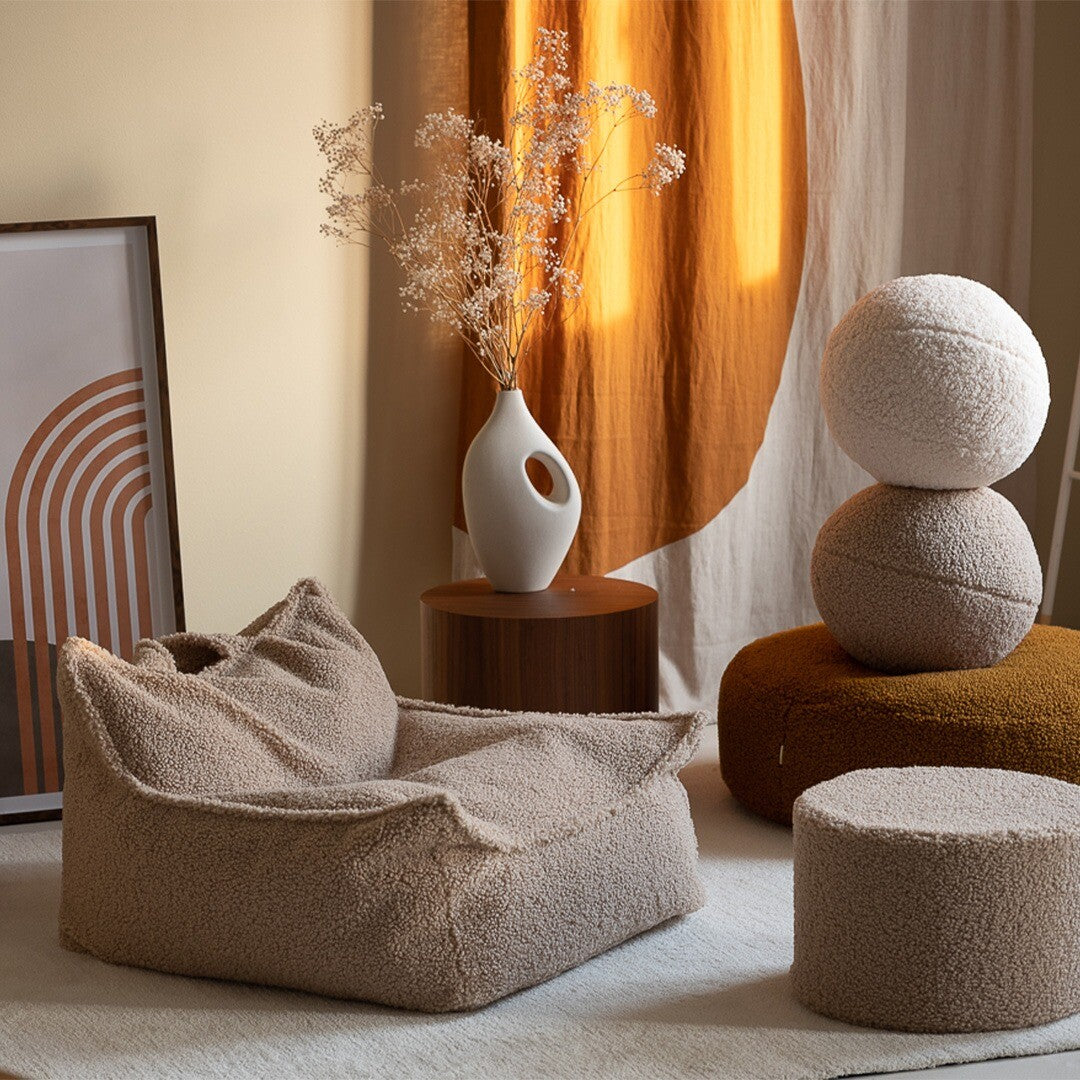 De Wigiwama beige kinderzitzak stoel staat in een sfeervolle kamer met bijpassende poefjes.