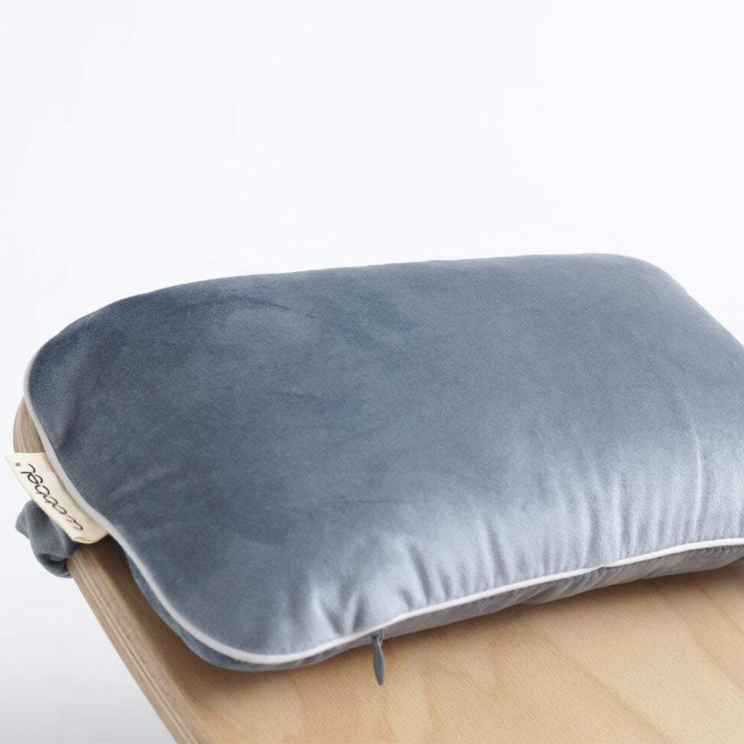 Wobbel kussen in aquamarine blauw fluweel met witte bies en rits, liggend op een houten Wobbel board.