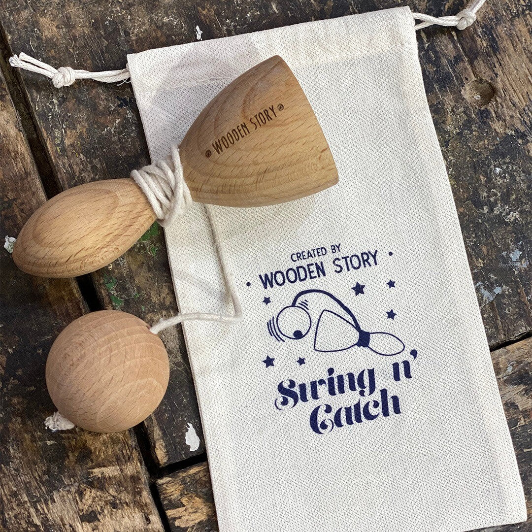 Wooden Story houten balvanger naast een witte stoffen zak met het logo en de tekst 'String n' Catch'.
