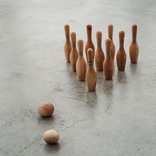 Het Wooden Story houten bowlingspel met tien kegels en twee ballen op een grijze betonnen vloer.