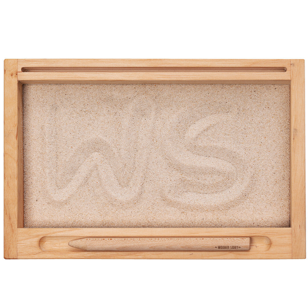 Wooden Story houten speelbak met zand en de letters 'WS' erin getekend, van bovenaf gezien.