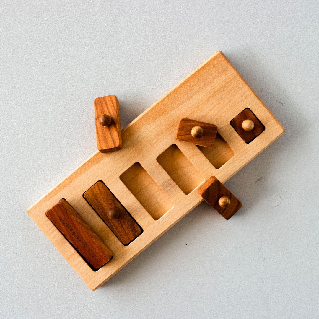 Wooden Story houten knoppuzzel van bovenaf gezien, met enkele bruine houten blokjes uit de lichte houten plank.