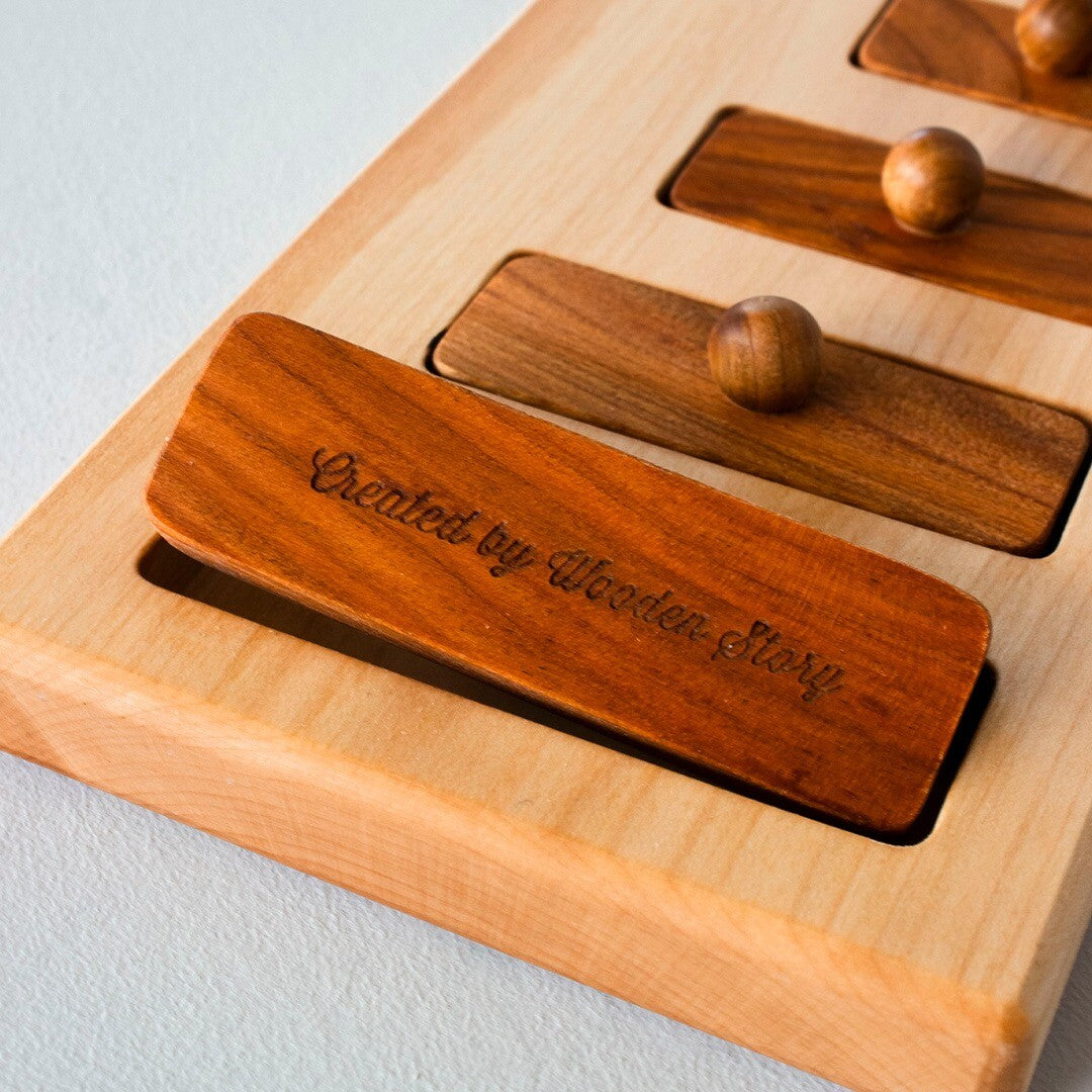 Detail van een bruin houten blokje van de Wooden Story knoppuzzel met de tekst "Created by Wooden Story" gegraveerd.