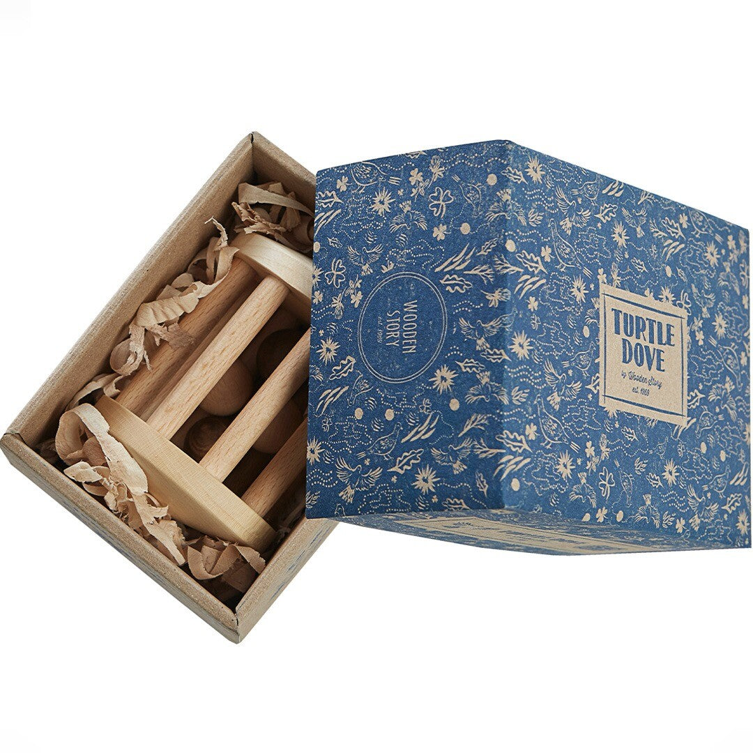 De open verpakking van de Wooden Story houten rammelaar, met het product en snippers papier erin.