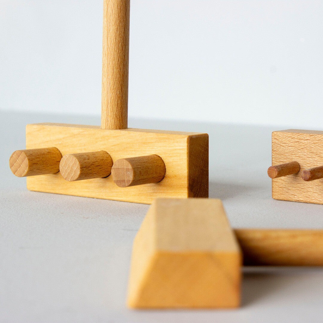 Detail van een Wooden Story houten speelbak accessoire met drie ronde pinnen.