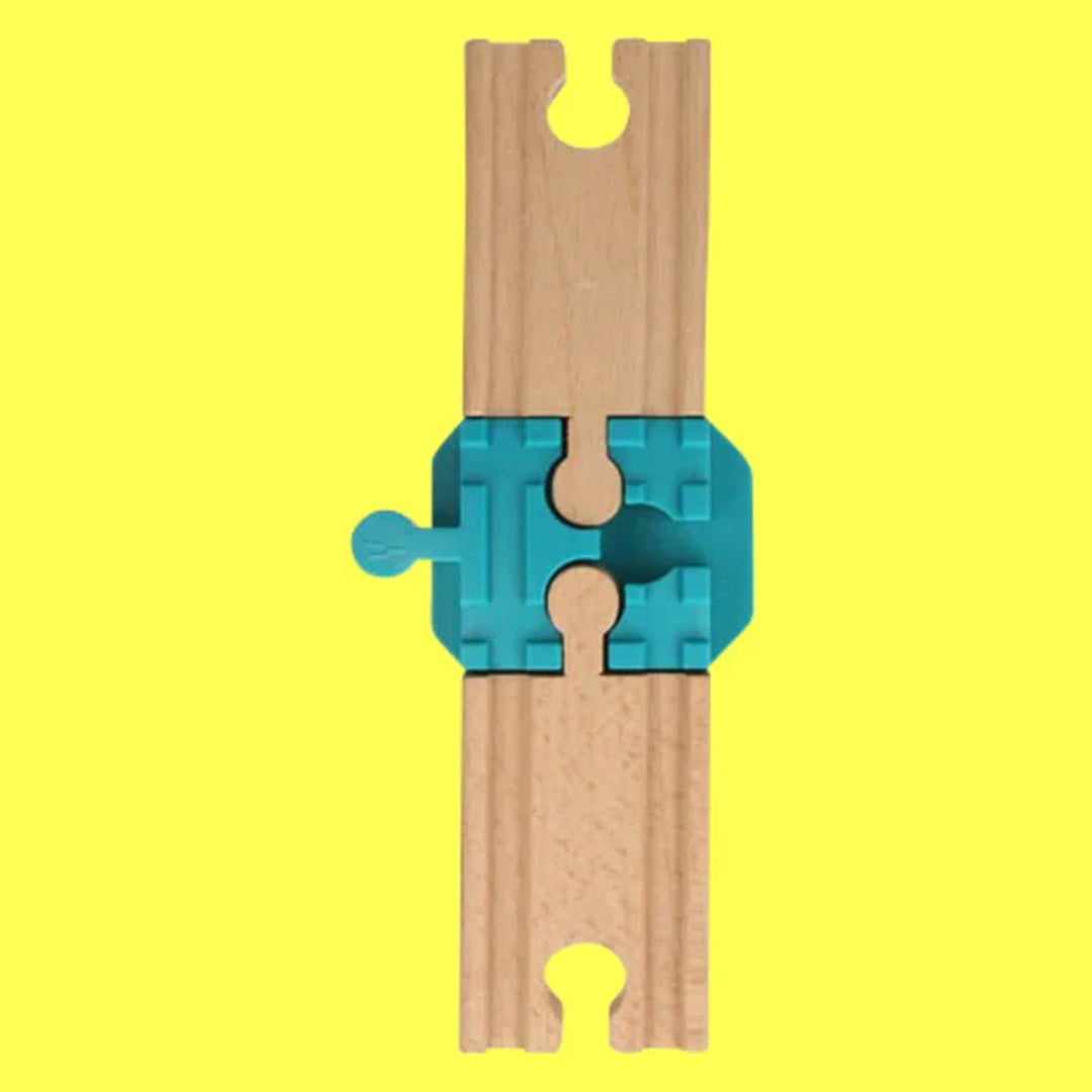 Een blauw plastic koppelstuk verbindt twee houten treinbaansegmenten in een rechte lijn op een gele achtergrond.