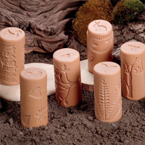 Zes beige Yellow Door kleistempels met bosdier- en natuurpatronen staan op een ondergrond van aarde en mos.