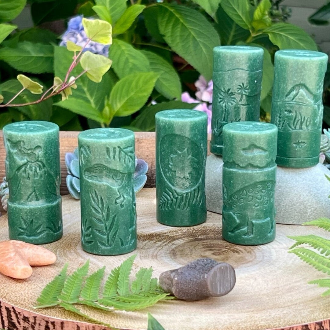 Zes groene Yellow Door kleistempels met diverse dinosaurus- en bladerpatronen staan rechtop op een houten schijf.