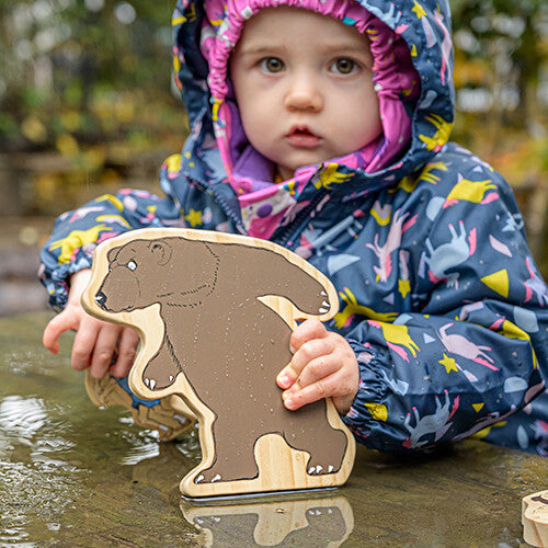 Een kind houdt de Yellow Door houten beer speelfiguur van de 'We're Going on a Bear Hunt' set vast.