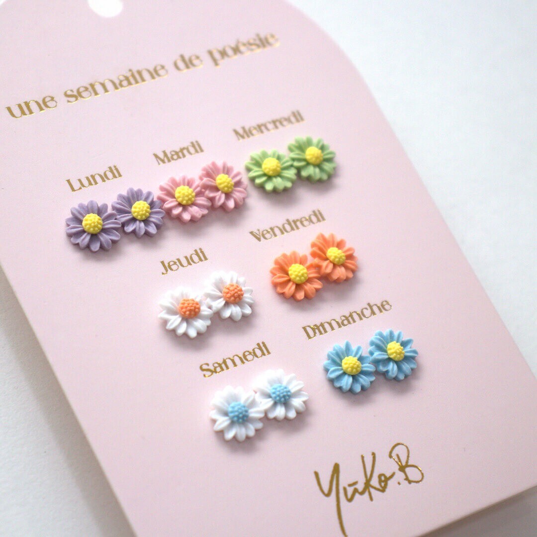 Yuko B. kinder oorknopjes set met 7 paar bloemvormige oorbellen in verschillende kleuren, schuin gefotografeerd op de roze verpakking.