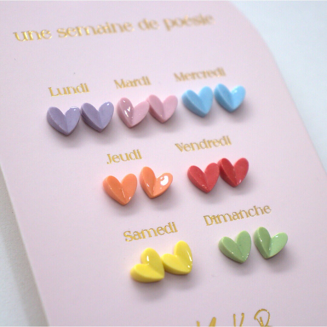 Detailopname van de Yuko B. kinder oorbellen met zeven paar hartjes oorknopjes in diverse kleuren op een roze kaart.