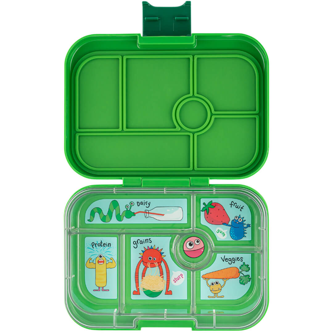 Open groene Yumbox lunchbox met zes vakken en grappige monster illustraties voor voedselgroepen.