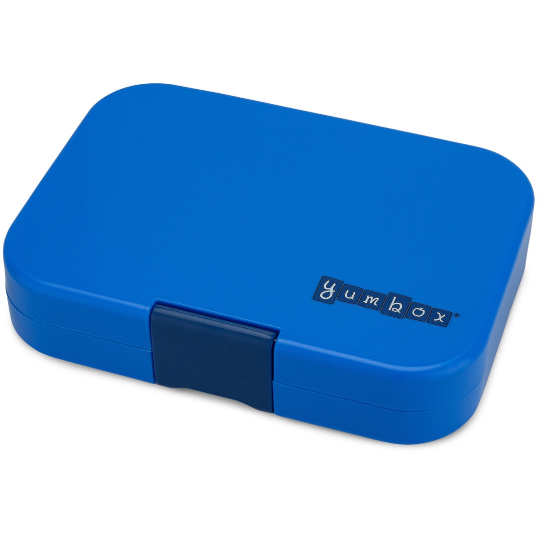 Gesloten blauwe Yumbox broodtrommel voor kinderen, schuin van bovenaf gefotografeerd.