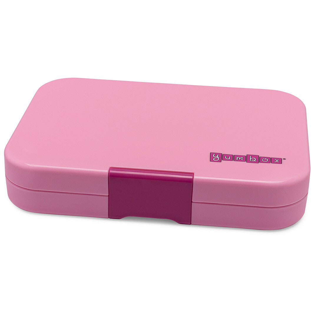 Gesloten roze Yumbox lunchcontainer voor kinderen, schuin van bovenaf gefotografeerd.