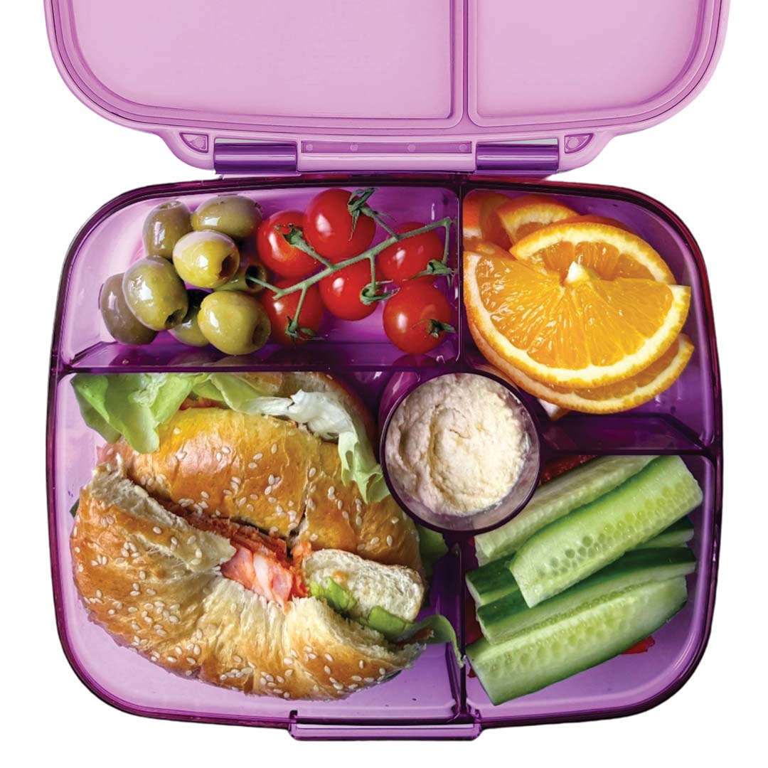 Yumbox bento broodtrommel gevuld met diverse etenswaren zoals olijven, tomaatjes, sinaasappel en een bagel.