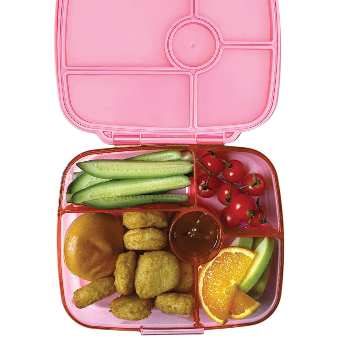 Roze Yumbox bento broodtrommel van bovenaf gevuld met komkommer, tomaatjes, kipnuggets, saus, sinaasappel en appel.