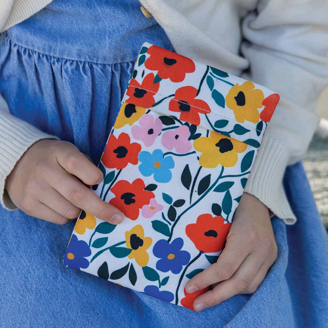 Een kind houdt een Yumbox koelelement met kleurrijk bloemenpatroon vast.