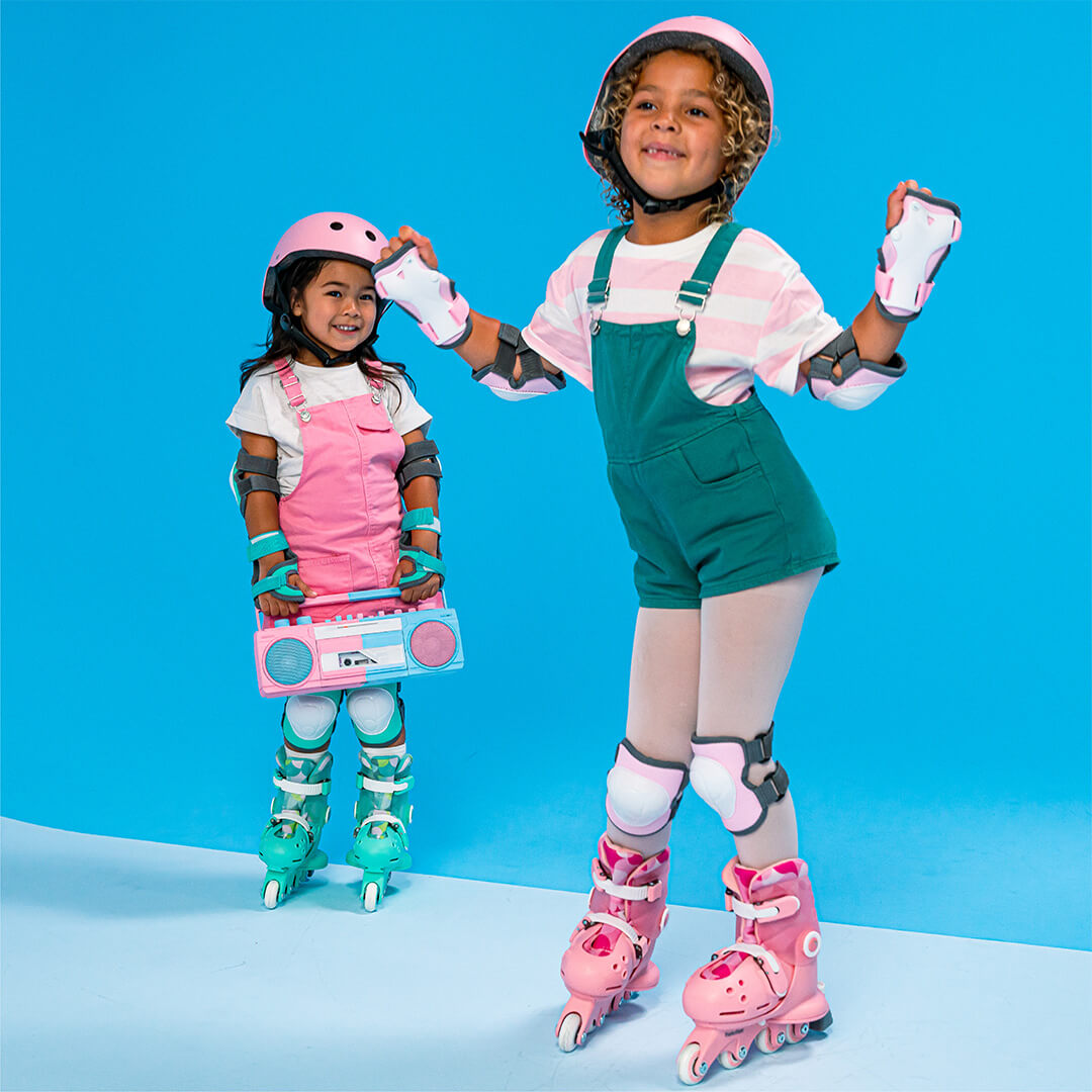 Twee kinderen met beschermende kleding en skeelers, waarvan één kind roze Yvolution kinderskeelers draagt.