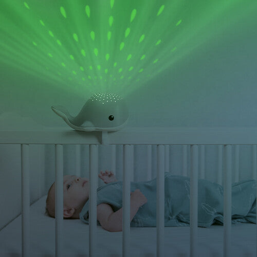 Zazu Wally muziekdoos en lichtprojector als grijze walvis projecteert groene lichtpatronen boven een slapende baby in een wieg.
