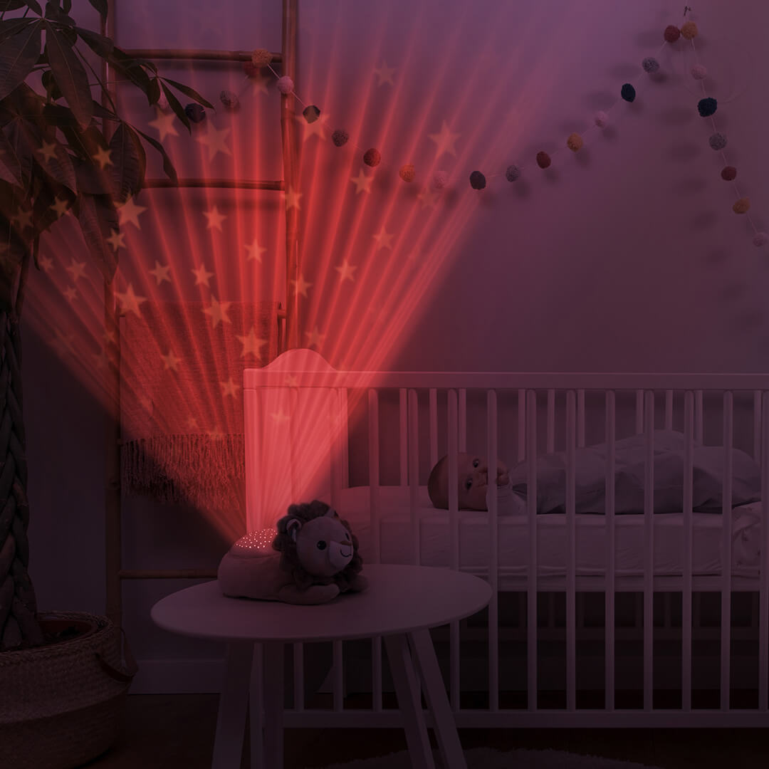 De Zazu leeuw sterprojector projecteert rode sterren op de muur naast een babywieg.