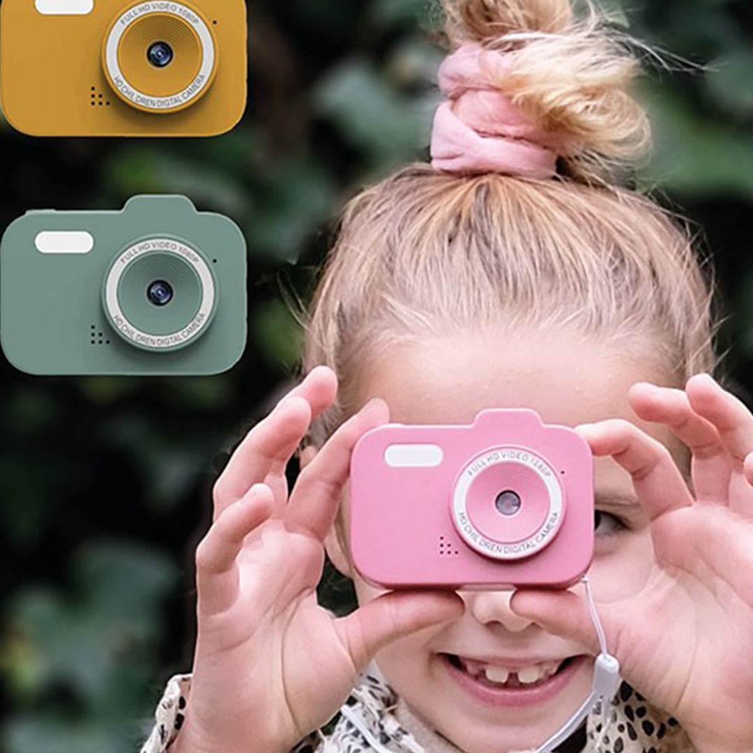 Een lachend meisje houdt een roze digitale kindercamera vast, met groene en gele camera's op de achtergrond.