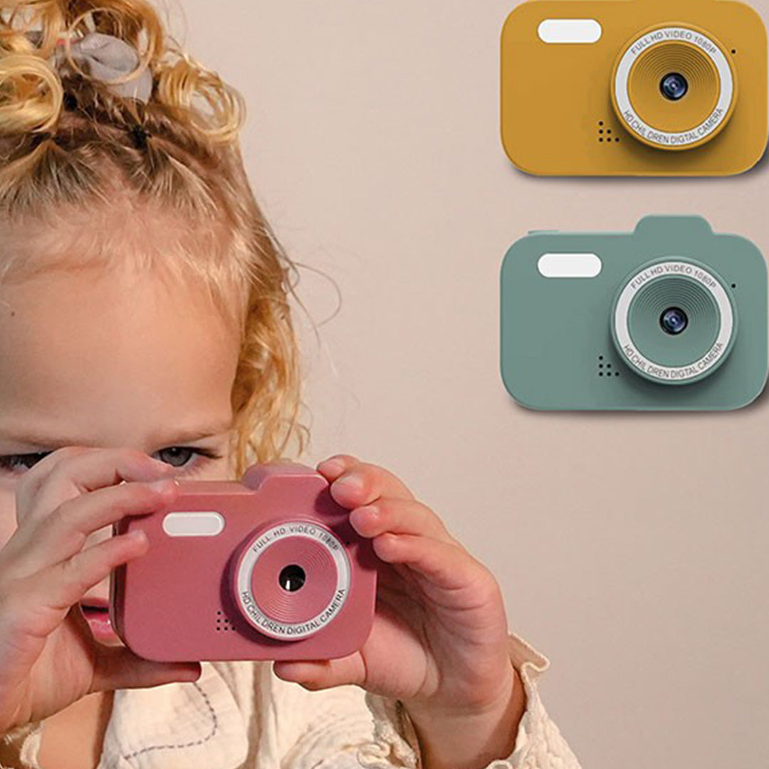 Een kind dat een roze digitale kindercamera vasthoudt, met op de achtergrond een gele en groene camera.