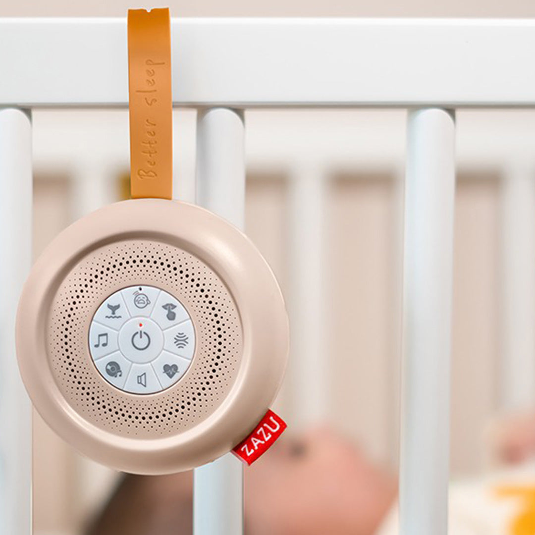 Zazu beige geluidsmachine hangend aan de spijlen van een wit babybedje.