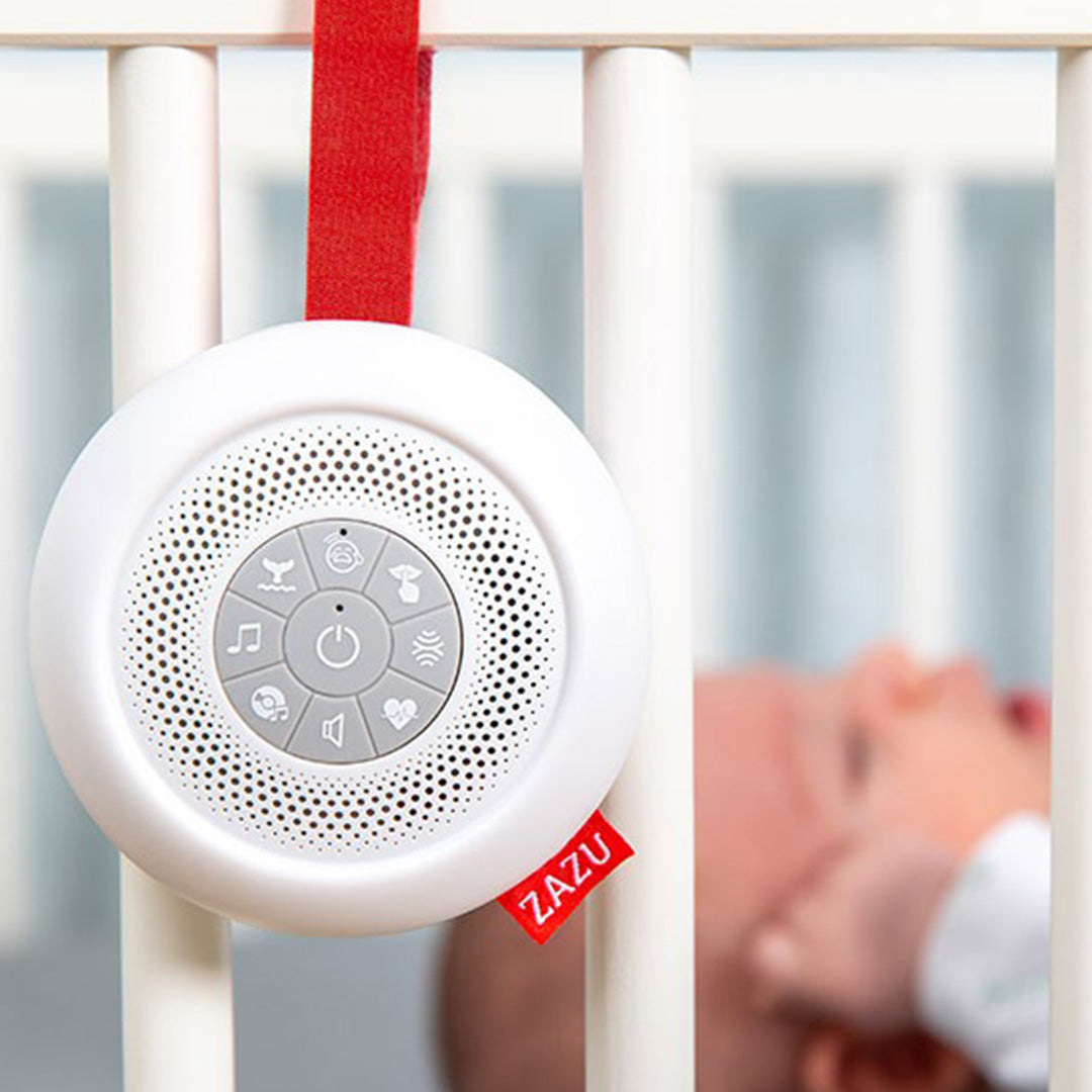 Zazu muziekdoosje Suzy hangt aan de spijlen van een babywieg, met een baby op de achtergrond.