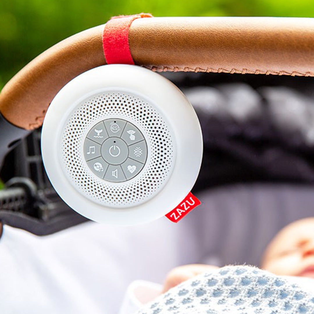 Zazu muziekdoosje Suzy hangt aan de duwstang van een kinderwagen, met een slapende baby erin.